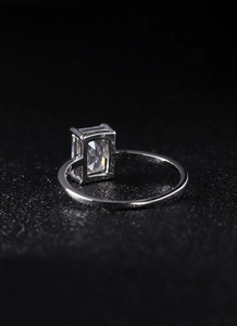 Close-up of a silver ring with a rectangular clear gemstone on black texture