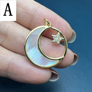 Detailed close-up of a gold-plated moon pendant with shell inlay and a sparkling star charm