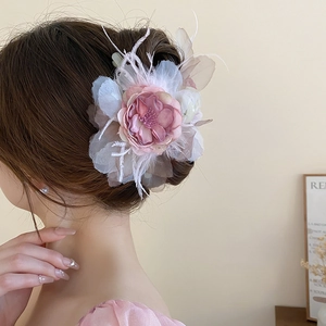 Elegant pink fabric flower hair claw with soft feathers shown on model back view