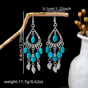 Size detail of bohemian hollow floral earrings with turquoise tassels on a wood branch
