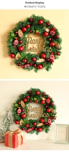 Detail von Weihnachts-Süßigkeitenkranz mit roten Kugeln, Holzscheiben und goldenem Weihnachtsgruß