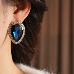 Vue détaillée de boucles d'oreilles vintage dorées avec gemme bleue et strass brillants