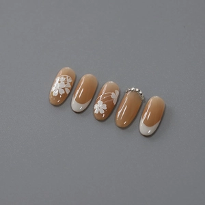 Elegant nude French manicure press-on nails with white floral art and subtle rhinestone accents