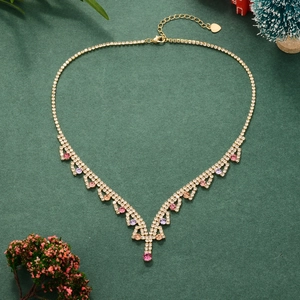 Elegant V-shaped gold necklace with pink and purple rhinestones on a festive backdrop