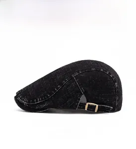 Detail view of black ivy cap with white grid texture and brass metal side buckle