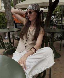 Outdoor street style view of beige V-neck linen vest and white wide-leg cotton shorts