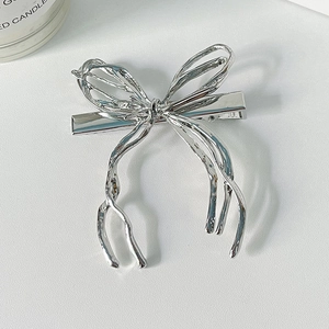 Minimalist liquid metal silver bow hair clip with irregular design on white background