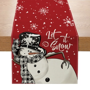 Detail of red linen Christmas table runner featuring a snowman and Let it Snow text