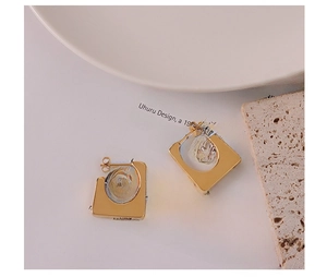 Detail view of gold geometric square earrings on a minimalist white paper background