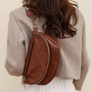 Close-up of retro brown leather chest bag with pebble texture and bronze hardware
