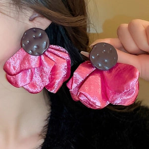Macro shot of large fuchsia silk flower earrings with textured dark center on model