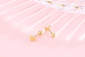 Detail of gold S925 butterfly stud earring with screw ball back on soft pink background