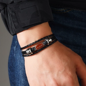 Close-up of men's leather bracelet featuring a brown American football bead and alloy clasp