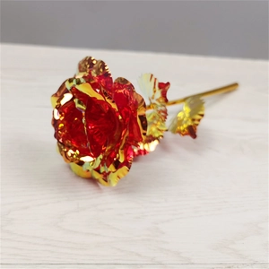 Macro detail of red gold foil rose blossom with golden stem on a wooden surface