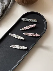 Detailed macro of marble texture hair clips with silver puppy and egg-shaped crystal deco