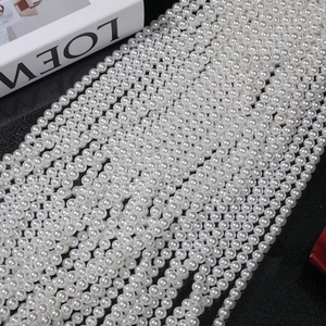 Close-up of polished white round 6-8mm imitation pearls on a black background