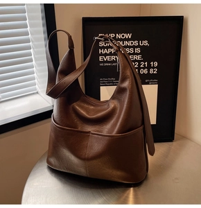 Detailed view of a brown vintage leather hobo bag with dual pockets on a metal table