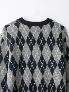 Detail of argyle knit pattern and crew neck collar on a gray textured sweater