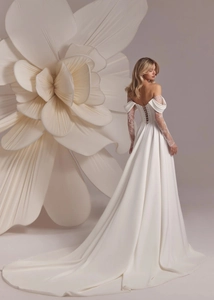 Detailed back view of white off-shoulder satin wedding gown with lace sleeves and corset back