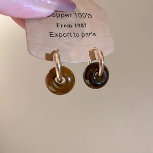 Detailed shot of vintage tiger eye geometric resin charms on golden hoop earrings