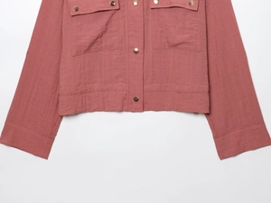 Detailed view of dust rose shirt jacket with gold buttons and large utility pockets