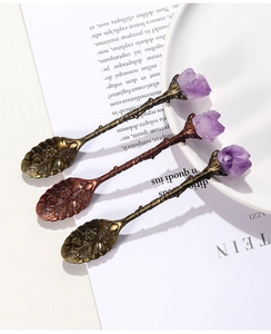 Close-up of vintage bronze spoons featuring carved floral handles and raw amethyst crystals