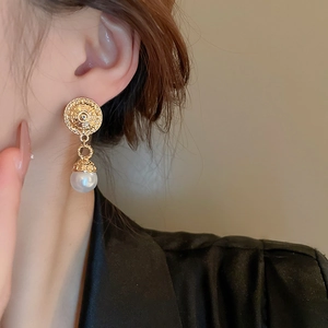 Close-up of model wearing a vintage gold relief earring with a white pearl drop