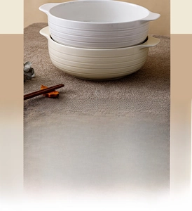 Detail of ceramic soup bowls with double handles and horizontal textured relief patterns