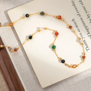 Minimalist colorful gemstone beaded necklace with fine gold chain on a wooden tray