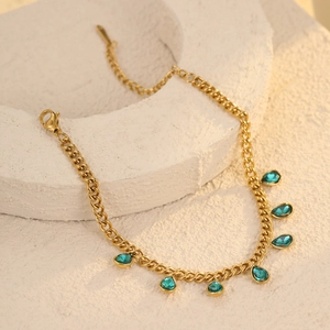 Detail of golden chain jewelry with seven light blue teardrop zircon stone pendants