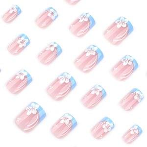 Short square press-on nails with blue French tips and white flower patterns on pink base