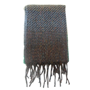 Detail view of a multicolored gradient scarf featuring thick fringe tassels and a soft knit