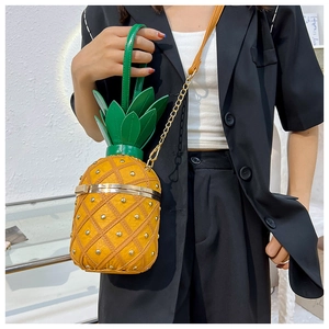Fashionable pineapple shaped crossbody bag with gold studs and green leaf top on model