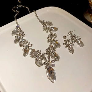 Exquisite silver necklace and earrings set with floral zircon clusters on a white tray