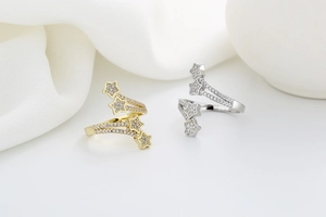 Detail of gold and silver star rings with pavé zircon settings on white silk background
