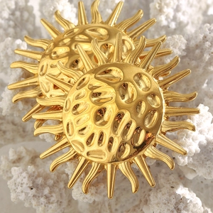 Macro shot of 18K gold plated sun stud earrings with hammered texture on white coral