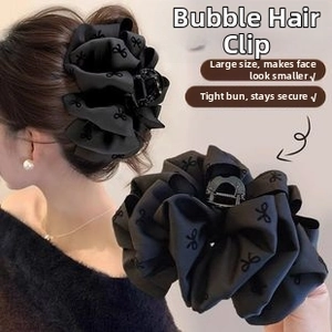 Macro view of large black bubble textured hair claw clip with delicate ribbon embroidery