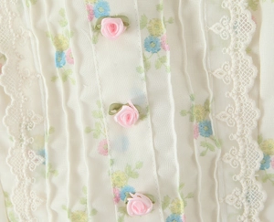 Détail du chemisier en dentelle florale avec roses 3D et texture de tissu plissé