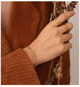 Model wearing a gold interlocking chain bracelet and two vintage style rings