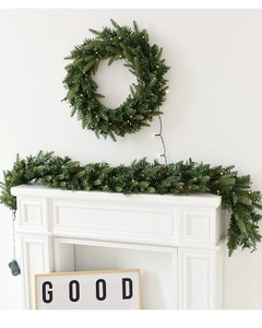 Détail d'une couronne de Noël en PE vert et guirlande avec LED chaudes sur une cheminée