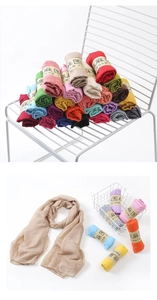 Detailed display of colorful cotton linen scarves stacked neatly on a white metal chair
