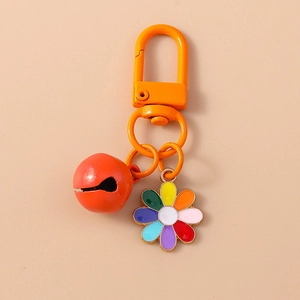 Macro view of orange metal keychain with colorful flower pendant and bell detail