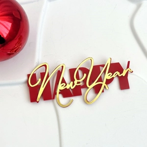 Close-up of Happy New Year cake topper with double-layer red and gold acrylic design