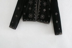 Détail de broderie ethnique argentée sur une veste en velours de soie noire
