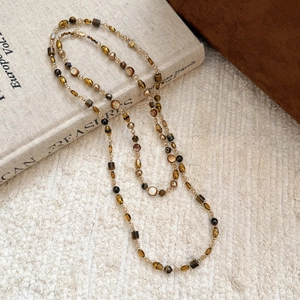 Détail d'un collier long vintage style oeil de tigre avec perles ambre et nacre