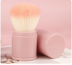 Detail of retractable makeup brush with pink gradient bristles and matching protective cap