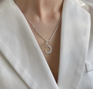 Close-up of 925 silver crescent moon necklace with textured finish and OT toggle clasp