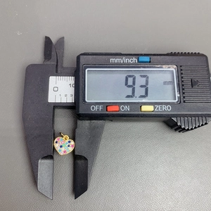Macro shot showing 9.3mm width measurement of a gold crystal heart pendant with digital caliper