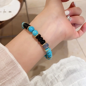 Detail of beaded bracelet with turquoise, black agate and gold spacers on a wrist