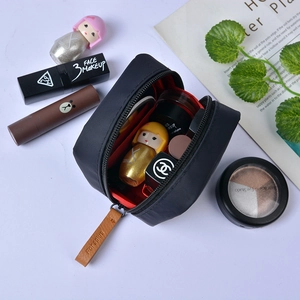 Portable black nylon lipstick storage bag with brown leather zipper pull and red lining